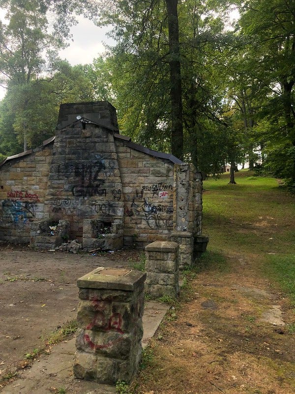 The old stone shelter with trees in the background and lots of graffiti.