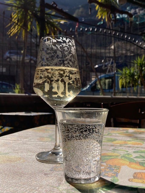 Empty plate of pasta with a hand holding a piece of bread mopping up sauce, with the second photo showing glasses of wine and sparkling water.