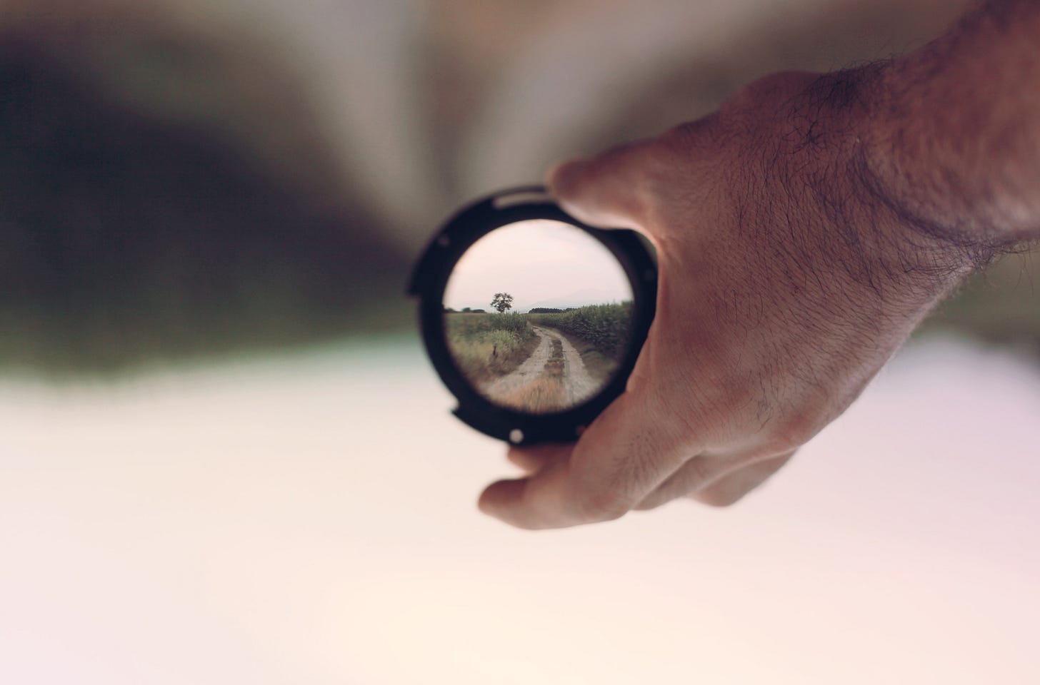 Hand holding lens bringing road into focus.