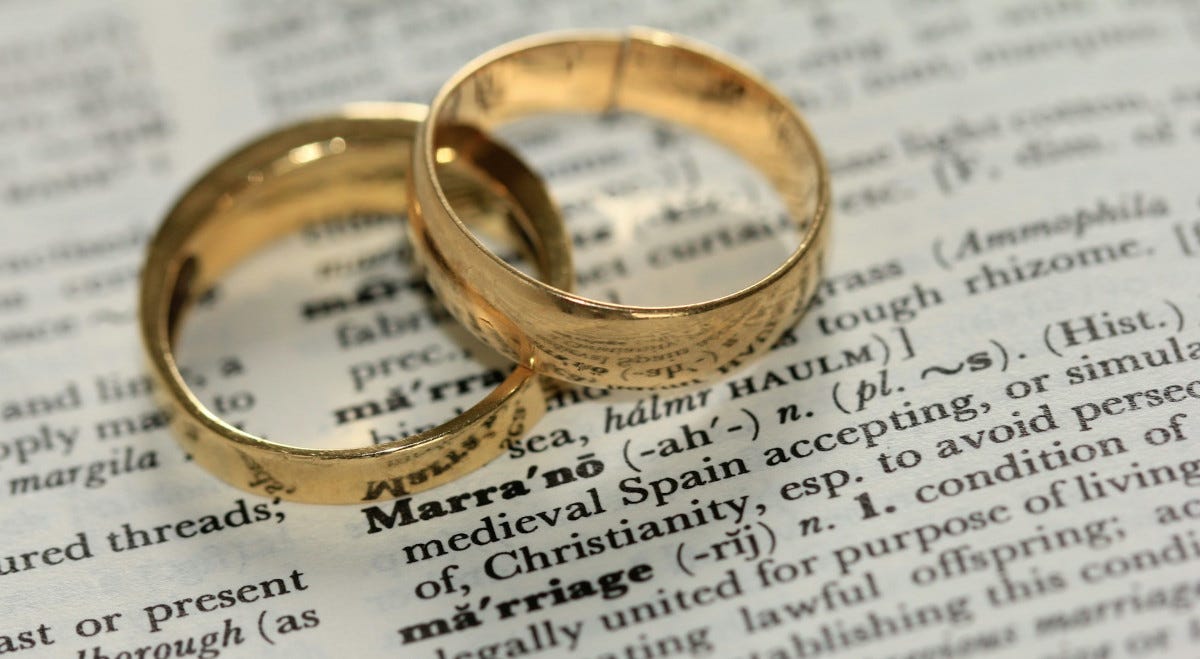 Two wedding rings atop a dictionary open to the page with ‘marriage’ on it. Two wedding rings atop a dictionary open to the page with ‘marriage’ on it.