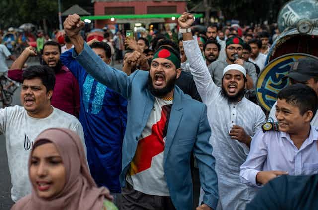 Men with raised fists march down a street. Men with raised fists march down a street.
