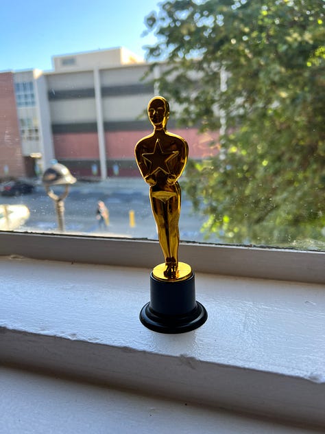 Image 1: Retirement door decoration; Image 2: Movie Night balloons hung on a wall; Image 3: A podium decorated like the Academy Awards; Image 4: A table of retirement decorations and pictures; Image 5: A tree with stars containing funny sayings; Image 6: A giant fake boom box and retirement decorations; Image 7: A tiny fake Oscar statuette; Image 8: An office door with retirement decorations; Image 9: A table with a tiny fake Oscar statuette and a balloon