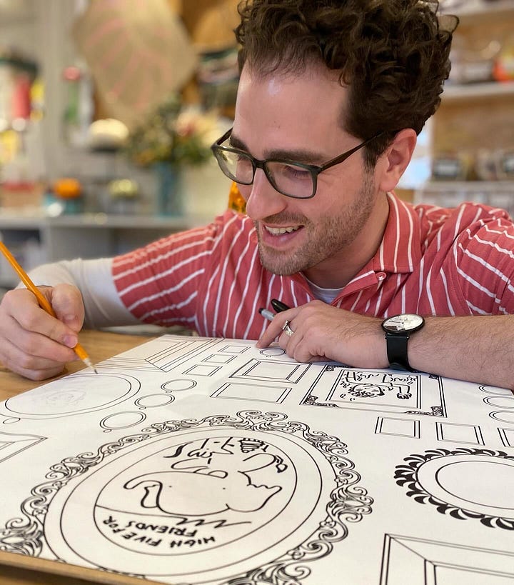 Jarad drawing a picture of Jay from A-Okay on an artist wall [left] and signing a copy of A-Okay [right]