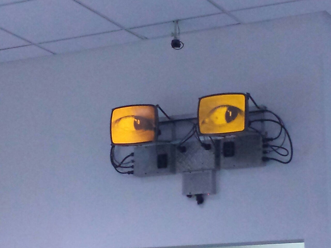 A wall-mounted security camera in yellow-orange housing.