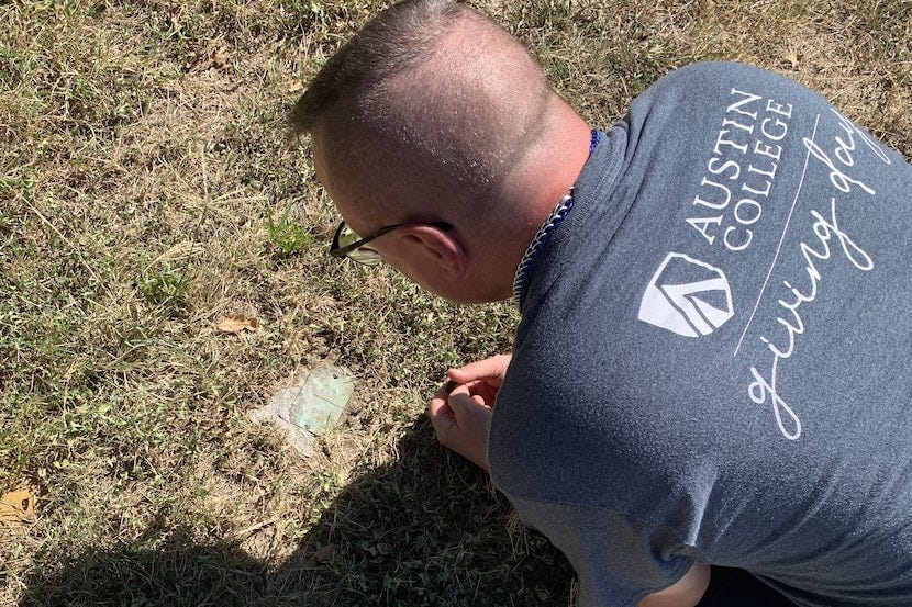 Daniel Babb leans over one of the few surviving markers at the Dallas City Cemetery. We...