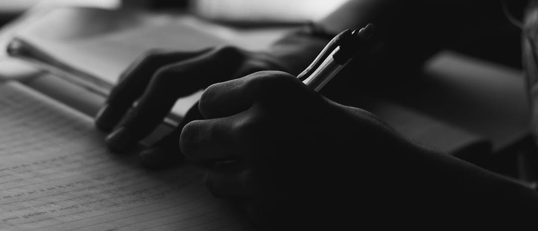 a person writing on a notebook with a pen