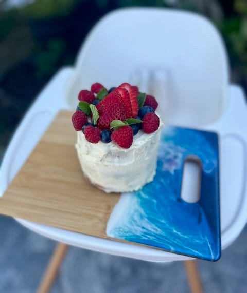 High chair with a small cake covered in berries