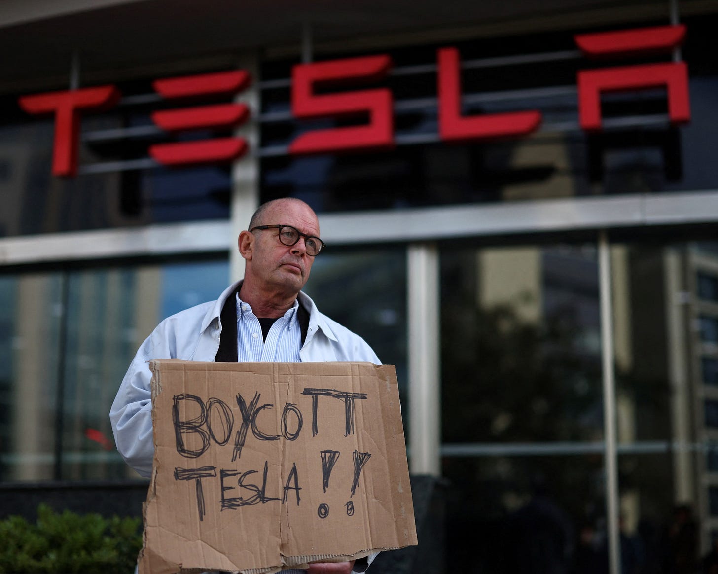 A person protests against Tesla and Elon Musk outside of a Tesla dealership in Lisbon