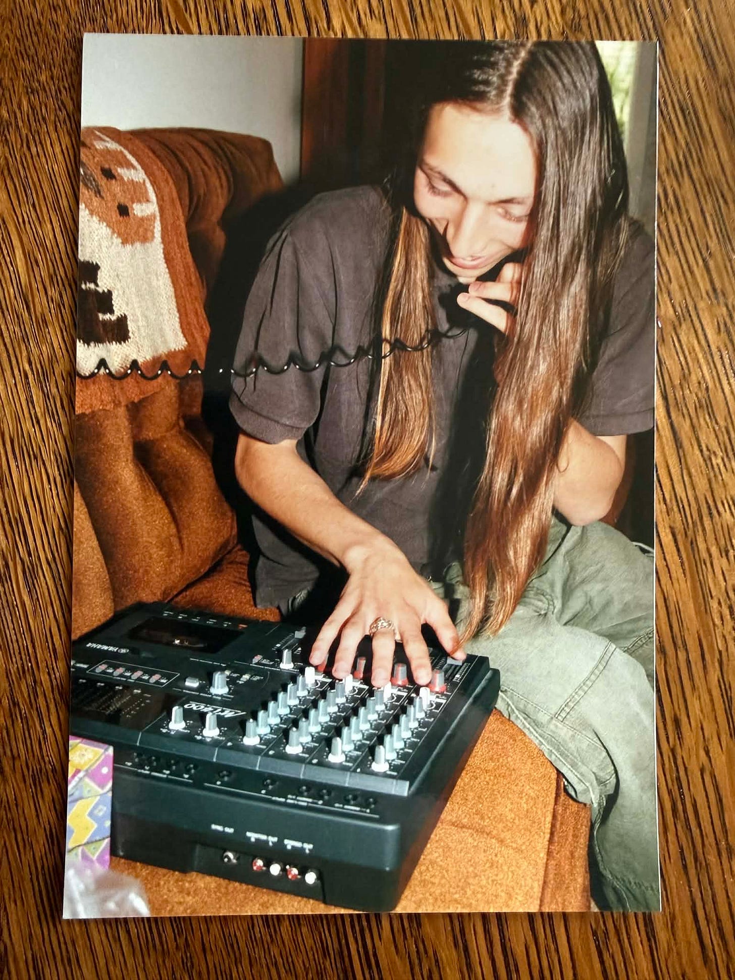 Ira, with long hair and a smile, sits on a brown couch while talking on a corded phone and operating a multitrack cassette recorder. Ira, with long hair and a smile, sits on a brown couch while talking on a corded phone and operating a multitrack cassette recorder.