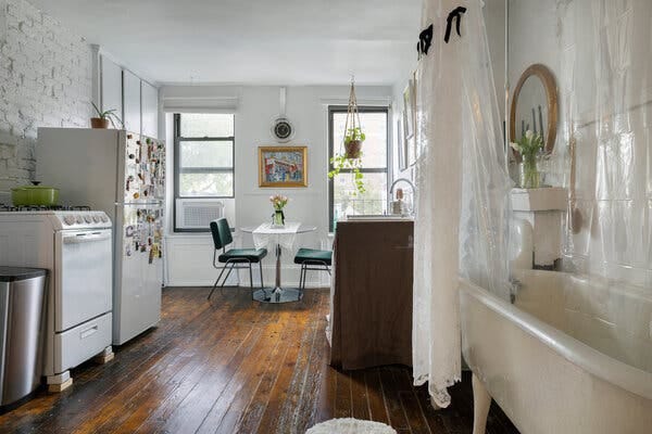 A wide shot shows a New York City kitchen that sports a claw-foot bathtub directly across from the oven. The kitchen sink is to the left of the bathtub, and across from the sink is a white refrigerator.