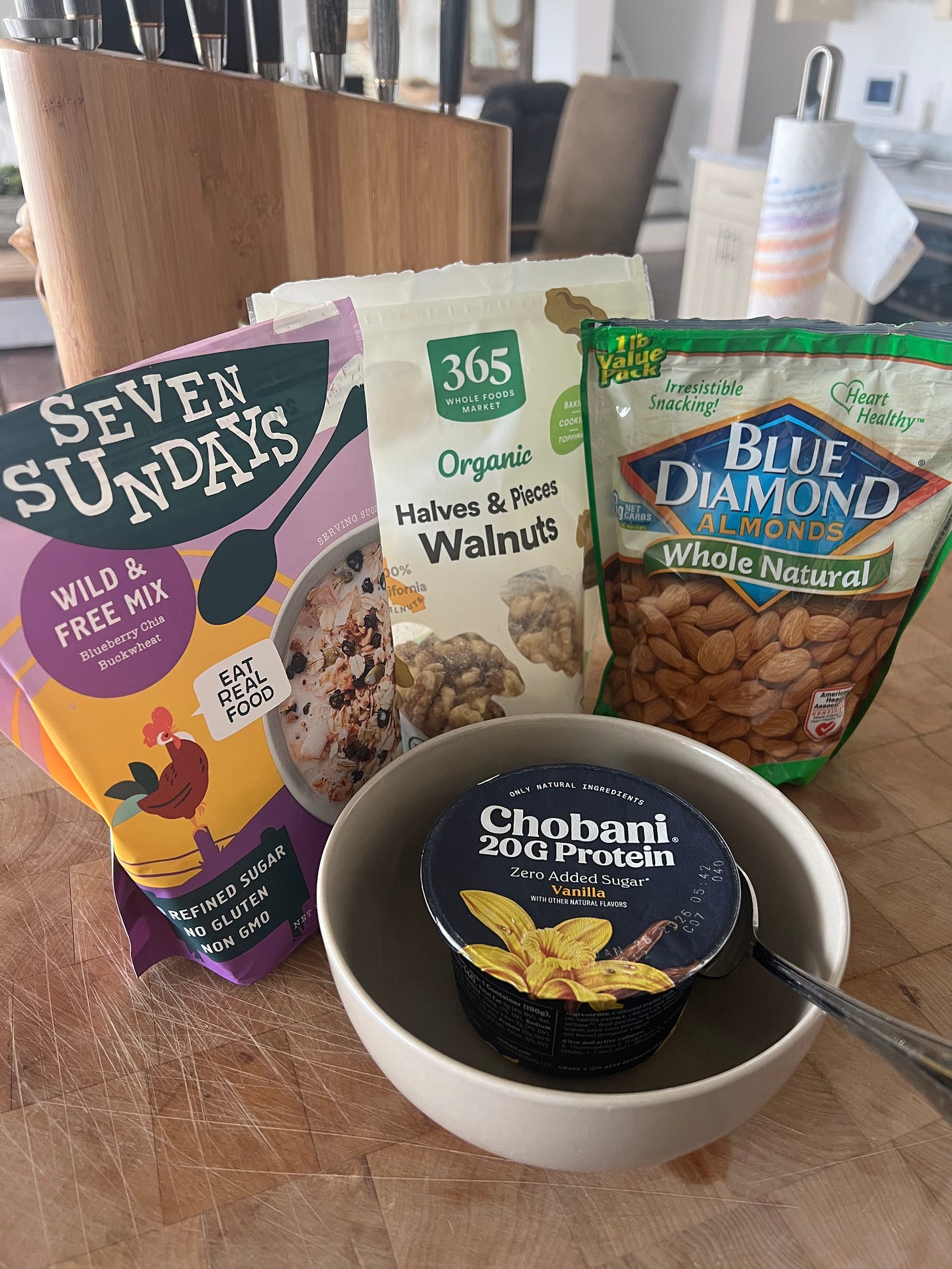 Donna Francis' high-protein breakfast line-up for The Beauty Ed®: A flatlay of muesli mix, organic walnuts, whole natural almonds, and Chobani vanilla yogurt, highlighting a "refined sugar-free" start to the New Year.
