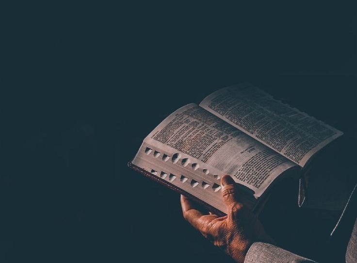 This may contain: a person holding an open book in their hands