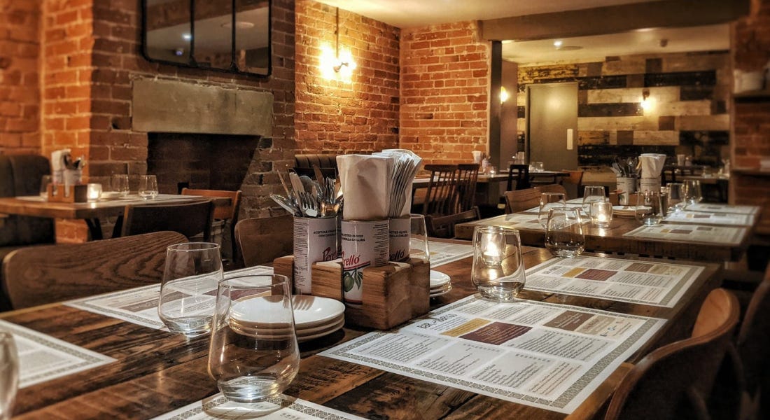 A restaurant with a brick wall and wooden tables with menus and glasses on A restaurant with a brick wall and wooden tables with menus and glasses on