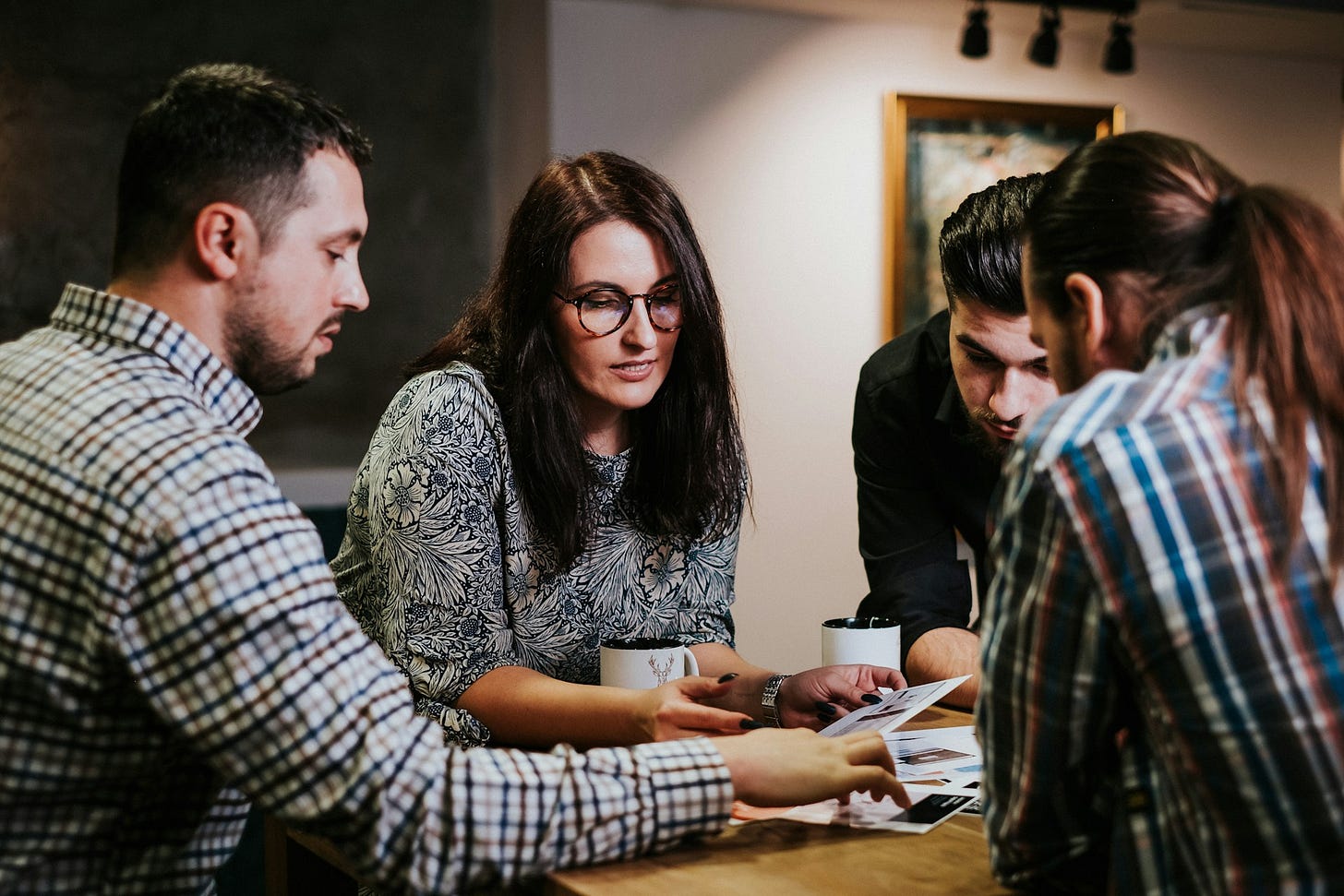 People sitting at a desk looking at papers. Photo by Andreea Avramescu on Unsplash