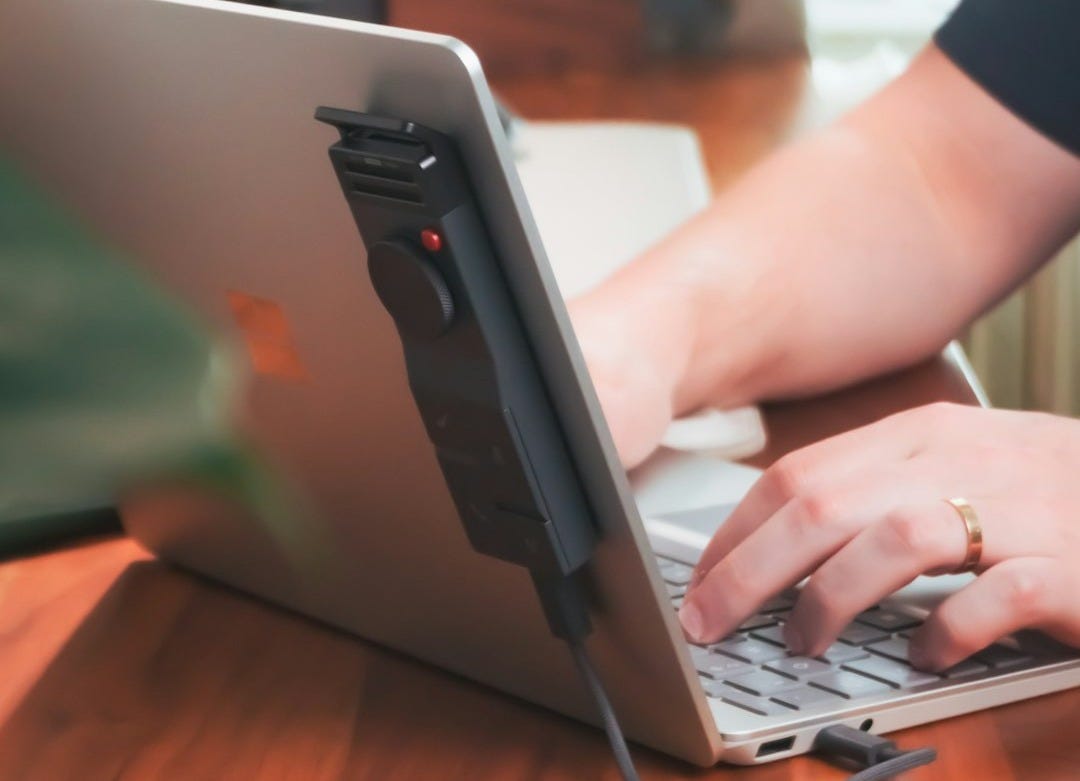 Someone is using a laptop with a device.