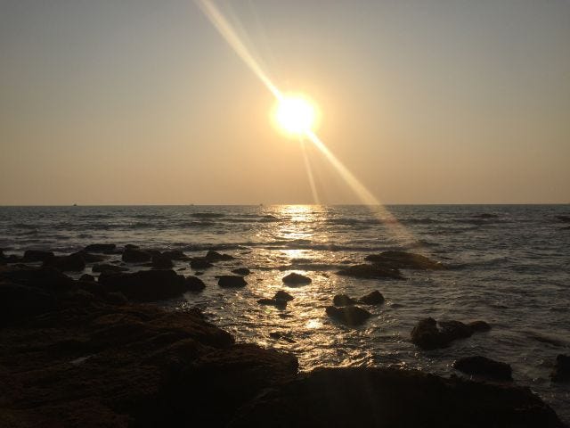 A sunset on waters with rocks in the ocean. A sunset on waters with rocks in the ocean.