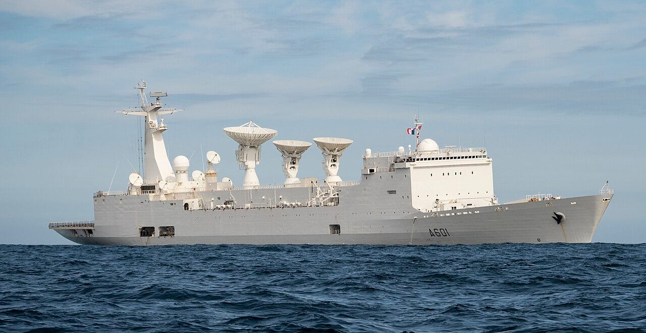 A large white French Navy ship with hull number A601 and three big tracking radar dishes on its upper deck, at sea under a blue sky. A large white French Navy ship with hull number A601 and three big tracking radar dishes on its upper deck, at sea under a blue sky.