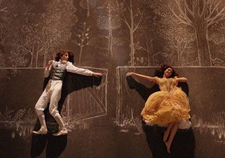 This may contain: two people dressed in costumes on stage with trees and foliage painted on the wall behind them