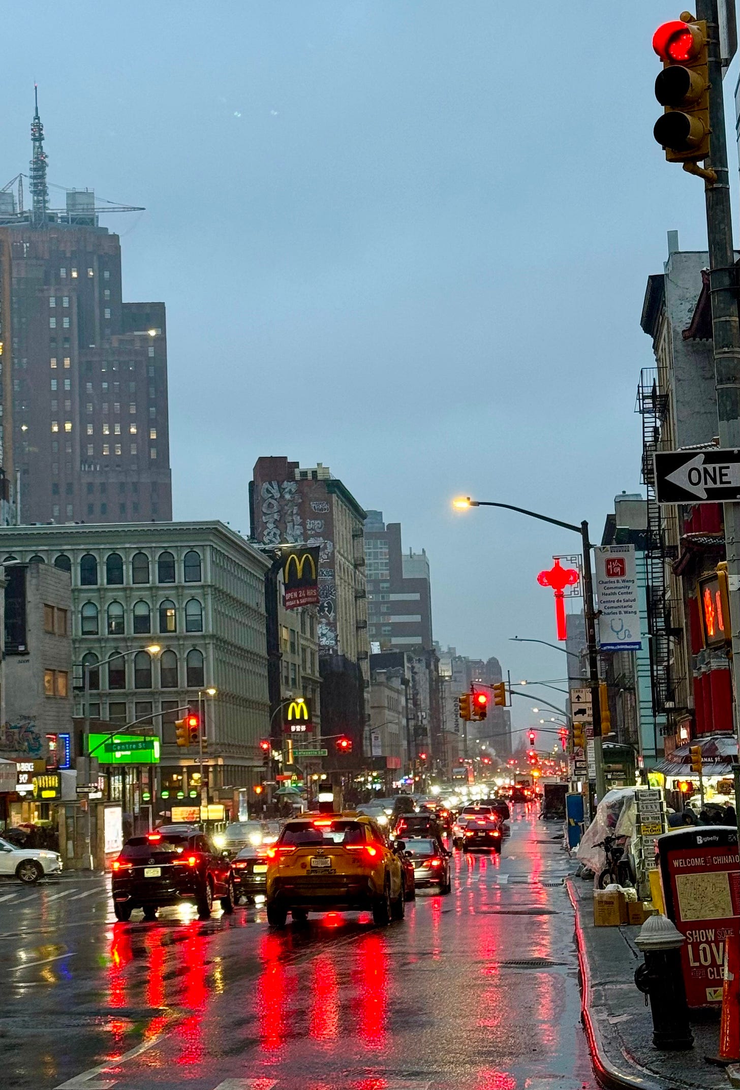 rainy canal street with red traffic lights reflecting off the ground nyc