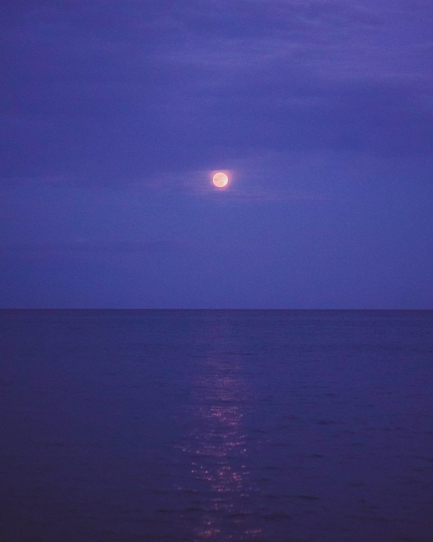 moon obscured by clouds reflecting on the ocean surface