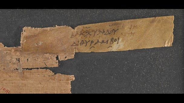 A small fragment of a 2nd-century papyrus scroll, with an attached parchment sillybos, or label, inscribed with the title of a work by Bacchylides. A small fragment of a 2nd-century papyrus scroll, with an attached parchment sillybos, or label, inscribed with the title of a work by Bacchylides.