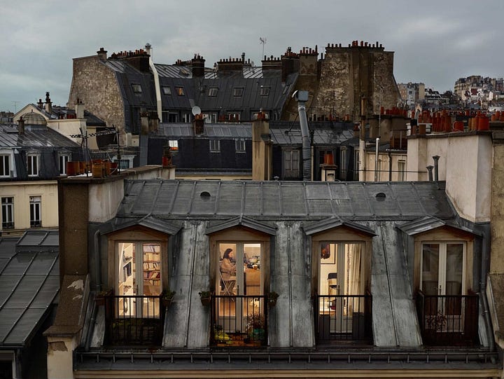 photographs of apartment windows in paris - you can see the people going about their daily lives inside, and in the second photo the Eiffel Tower is visible in the background