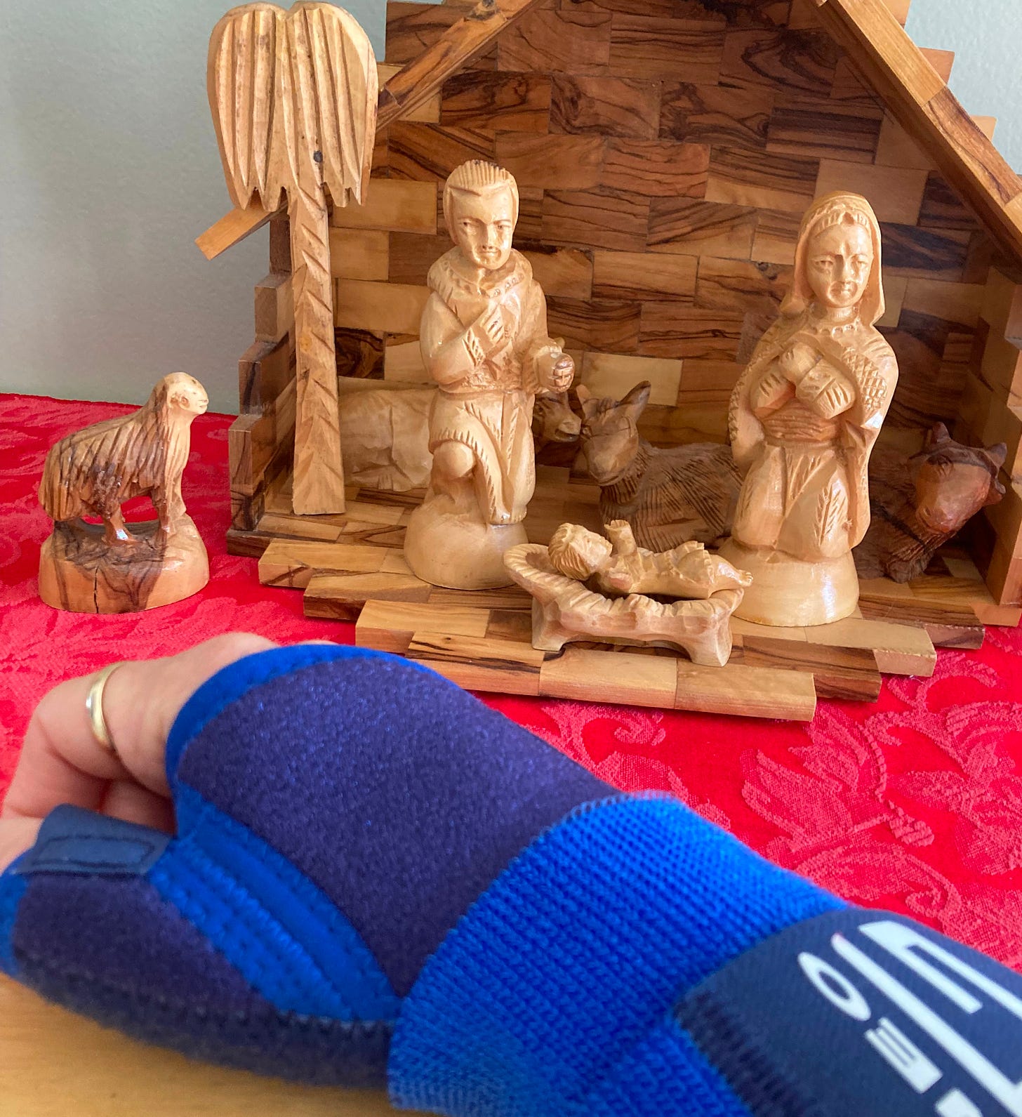 Just Come: picture of my hand in a blue support brace in front of a Christmas manger scene