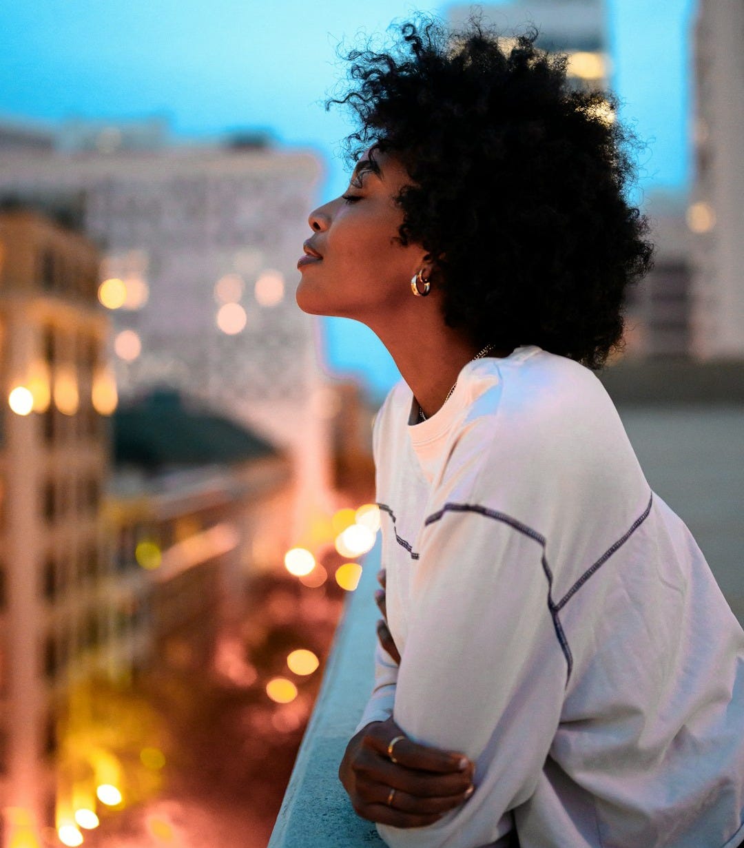 woman in white collared shirt looking at the city during night time woman in white collared shirt looking at the city during night time