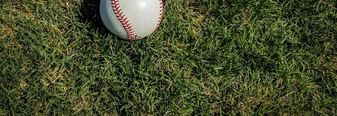 white and red baseball on green grass