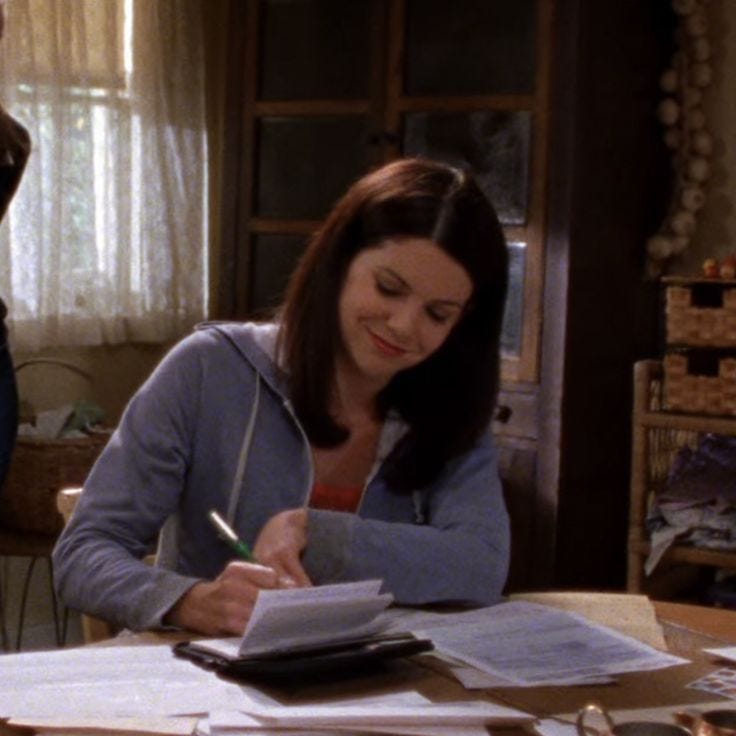 This may contain: a woman sitting at a table with papers and pen in her hand, writing on a piece of paper This may contain: a woman sitting at a table with papers and pen in her hand, writing on a piece of paper