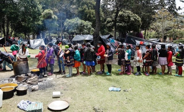 A line-up of Embera Katio women and children for food in the middle of Bogotá's national park, where displaced Indigenous people have had to set up camp this past month. Photo from CableNoticias A line-up of Embera Katio women and children for food in the middle of Bogotá's national park, where displaced Indigenous people have had to set up camp this past month. Photo from CableNoticias
