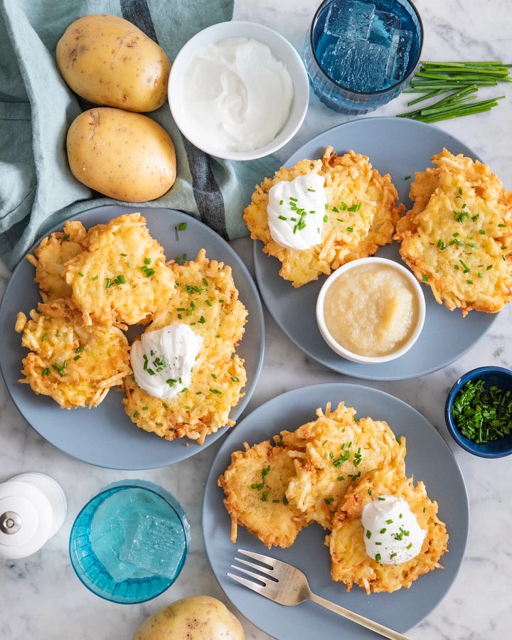 Chicken soup in a white bowl and three plates of potato latkes