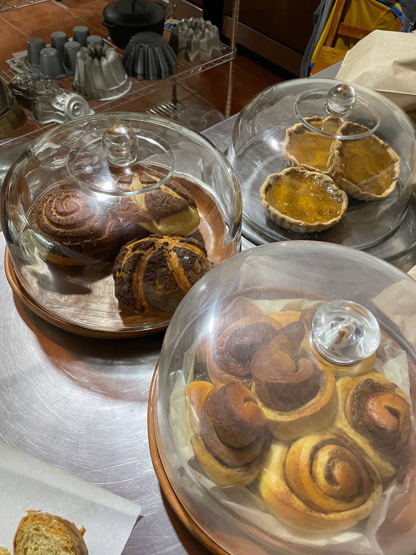 Three glass domes covering various types of baked goods.