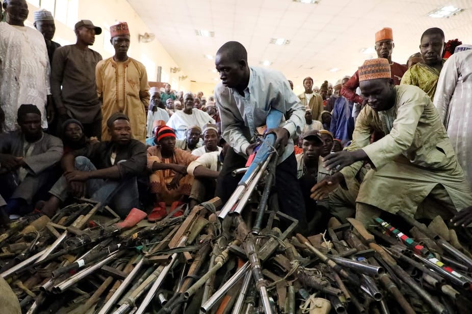 Men pilling up guns while others look Men pilling up guns while others look