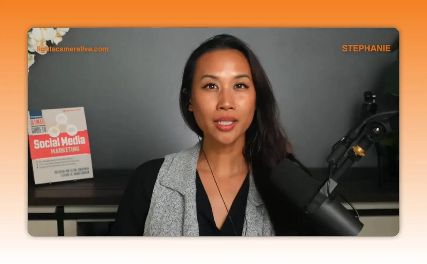 Host speaking into a professional microphone with a social media marketing book visible in the background. Host speaking into a professional microphone with a social media marketing book visible in the background.