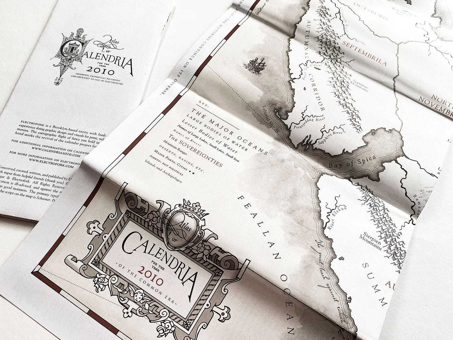 "Atlas of Calendria"- close up showing part of the map side, and the introduction text of a calendar-based novelty atlas
