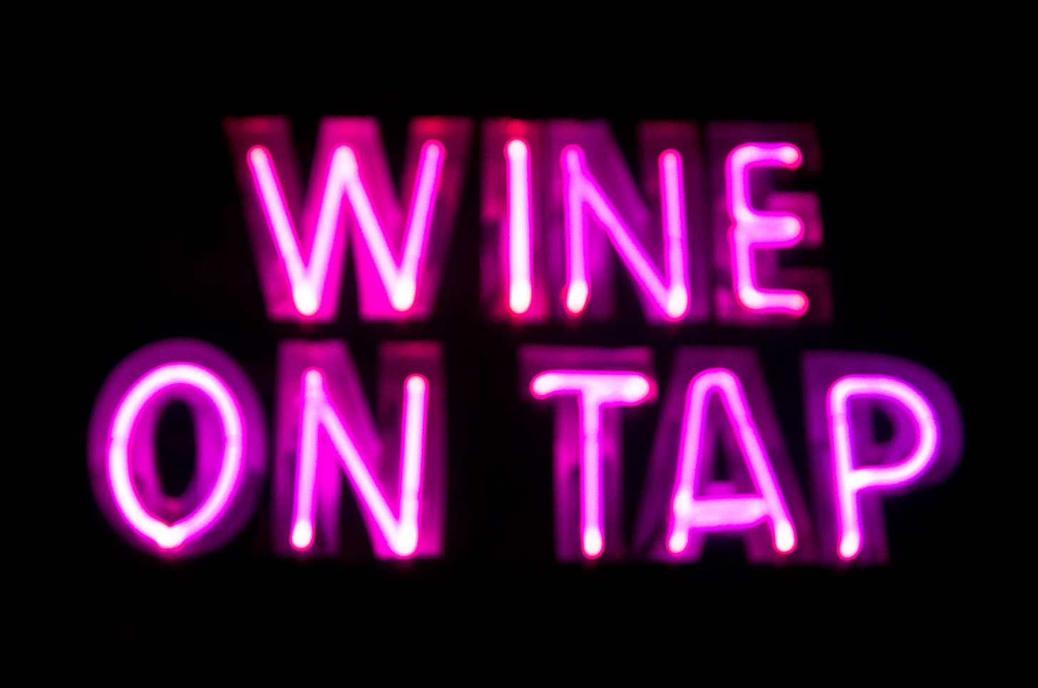 ID: Pink neon sign saying Wine on Tap