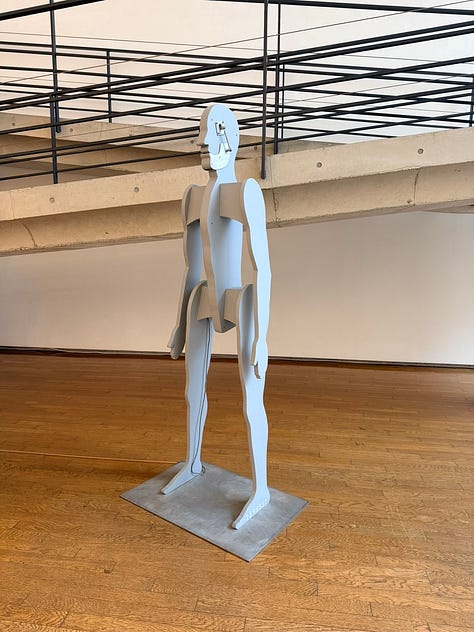 A grid of nine images depicting artworks by various artists, including Bruce Nauman, Jannis Kounellis, John Chamberlain, Yves Klein, Louise Nevelsen, Jenny Holzer, and Kan Yasuda.