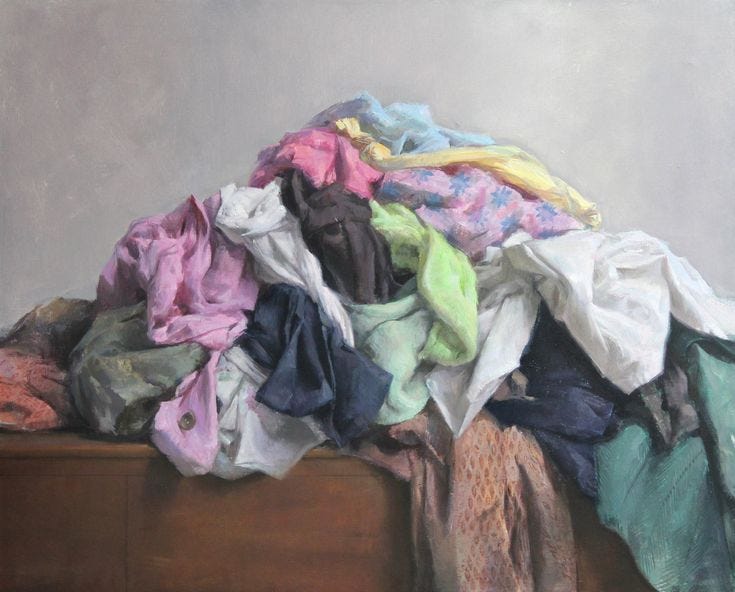 This may contain: a pile of clothes sitting on top of a wooden table next to a white wall
