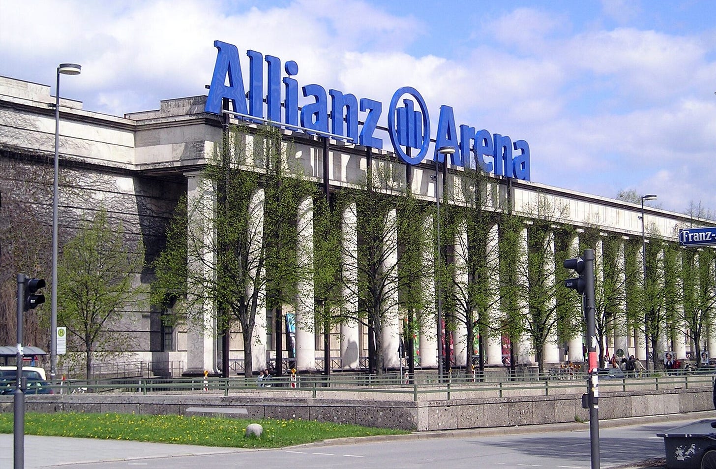 Auf dem Dach des Hauses steht zeitweilig das große blaue Logo „Allianz [Logo] Arena“, das ansonsten am Münchner Fußballstadion hängt
