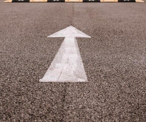white arrow sign on gray asphalt road