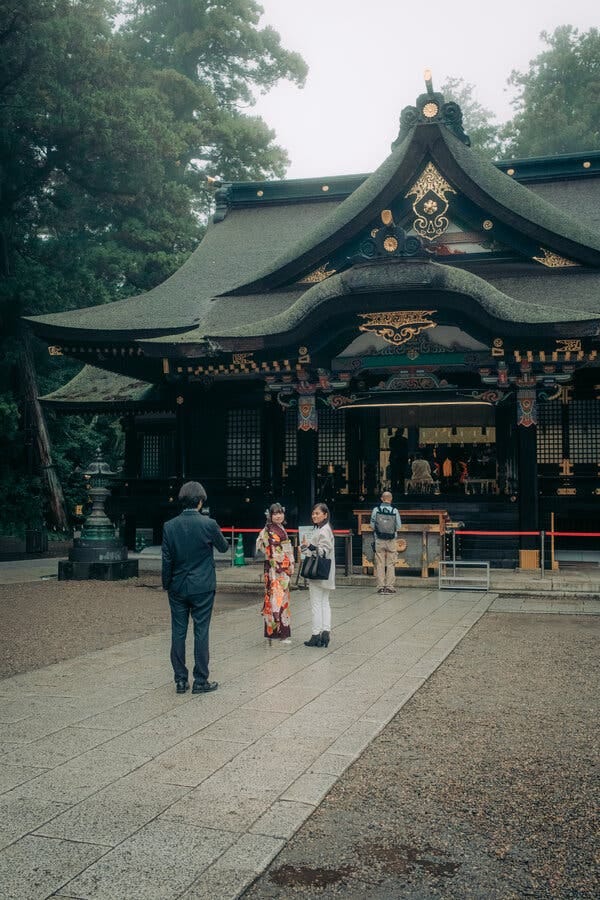 People in traditional garb and tourists outside a shrine. People in traditional garb and tourists outside a shrine.