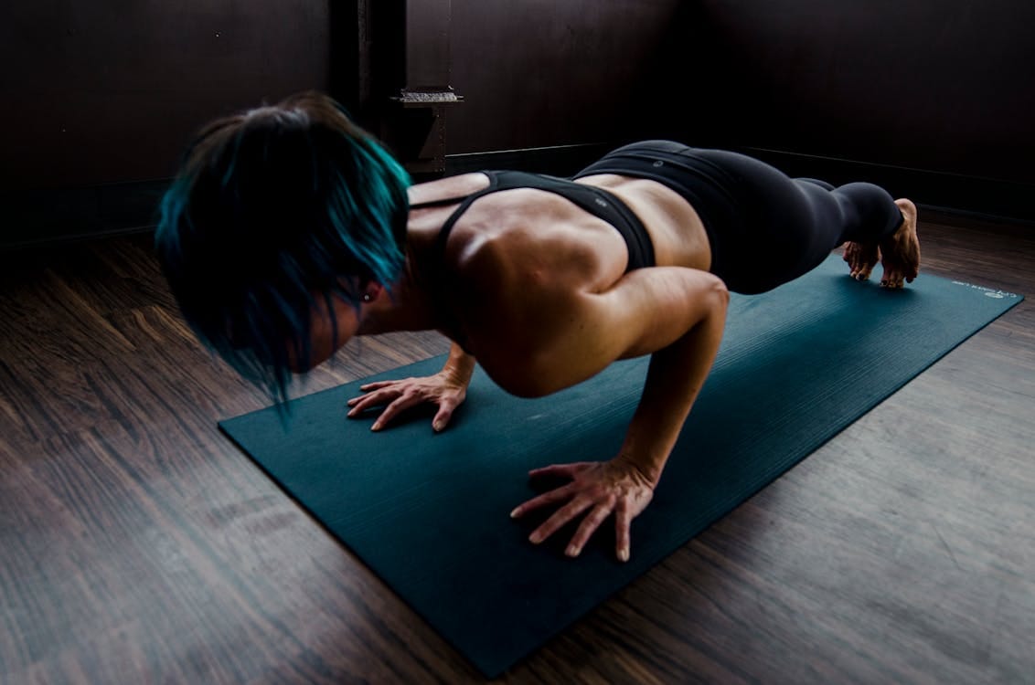 Free A fit woman with blue hair performs a push-up on a yoga mat indoors, showcasing strength and focus. Stock Photo Free A fit woman with blue hair performs a push-up on a yoga mat indoors, showcasing strength and focus. Stock Photo