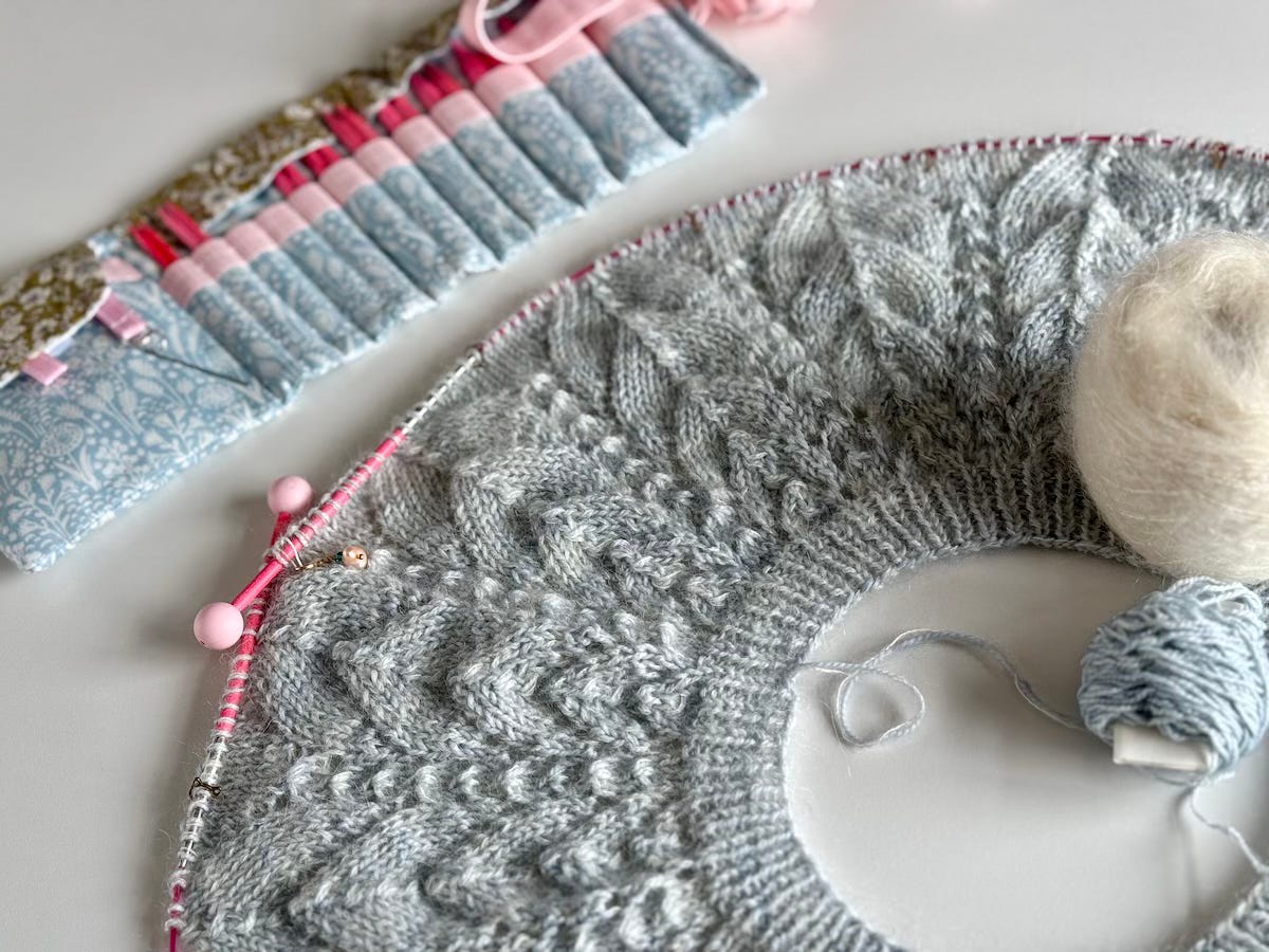 the knitted yoke of a Whitmoor Sweater with two balls of yarn and a set of interchangeable needles