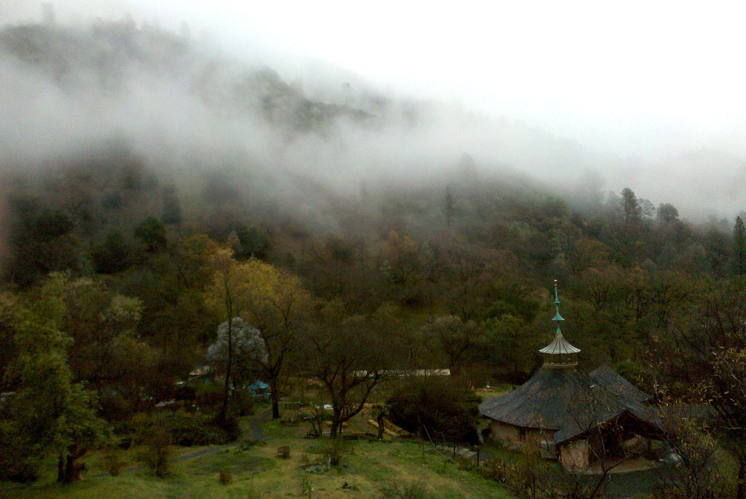 Fog rolling down a forested Northern California mountainside onto a peaked temple roof and wooded canyon at Harbin Hot Springs on a rainy day. Fog rolling down a forested Northern California mountainside onto a peaked temple roof and wooded canyon at Harbin Hot Springs on a rainy day.