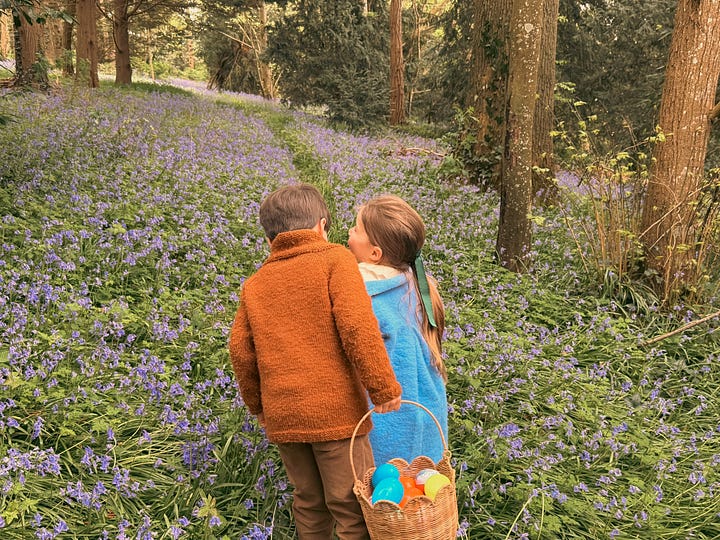 Two children searching for Easter eggs among bluebells in a French forest