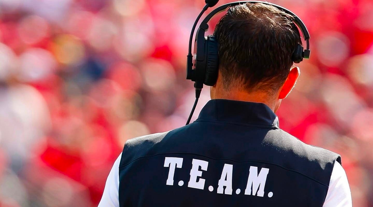 Wisconsin Badgers head coach Luke Fickell wearing a vest with “T.E.A.M.” printed across the back. Wisconsin Badgers head coach Luke Fickell wearing a vest with “T.E.A.M.” printed across the back.