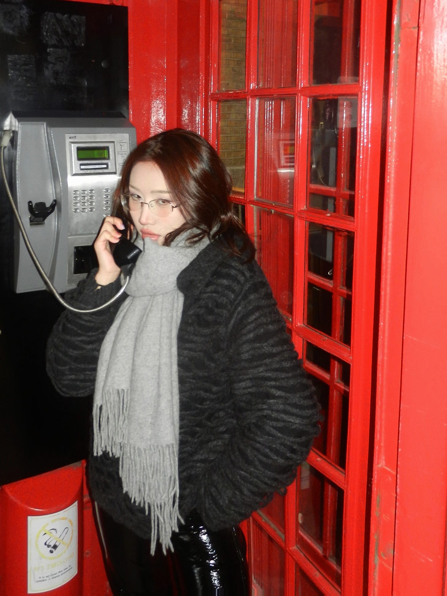 beautiful asian girl wearing fashionable japanese-style winter outfit posing in british iconic red telephone booth