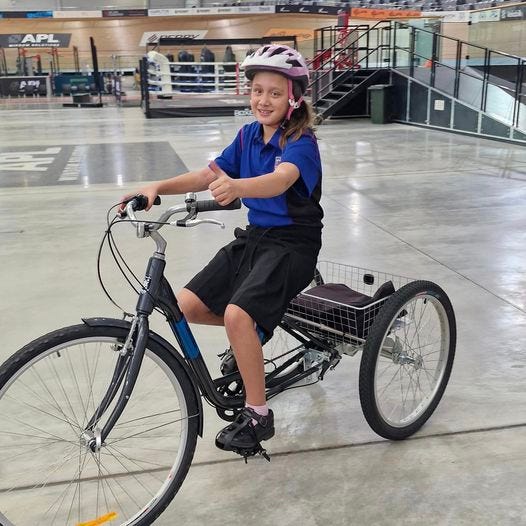 intermediate aged child on a suitably sized trike. she is smiling and giving the thumbs up. intermediate aged child on a suitably sized trike. she is smiling and giving the thumbs up.