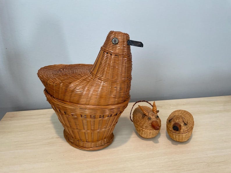 May include: Three woven wicker baskets. The largest basket is shaped like a bird with a black beak. The two smaller baskets are shaped like animals with brown and black details.